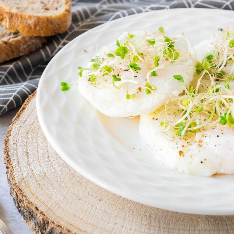 Thumbnail of poached eggs with watercress on top on wooden slab..
