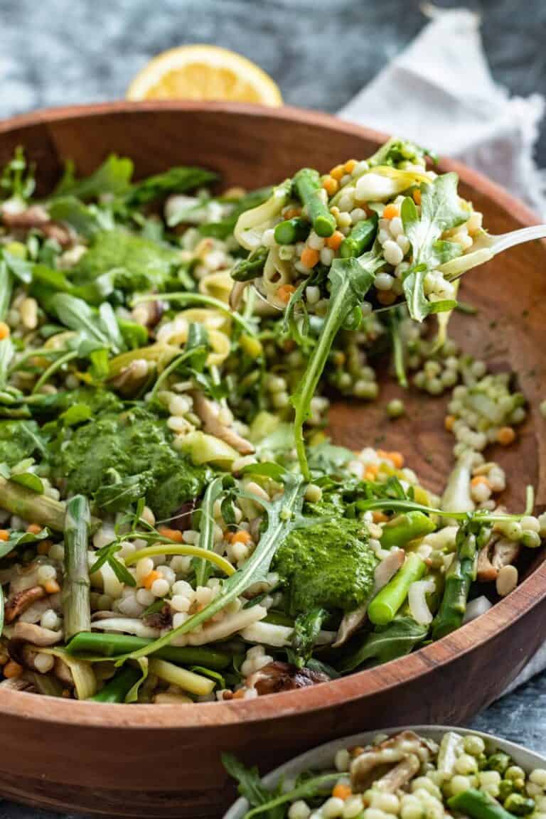 mushroom asparagus couscous salad in bowl with serving spoon