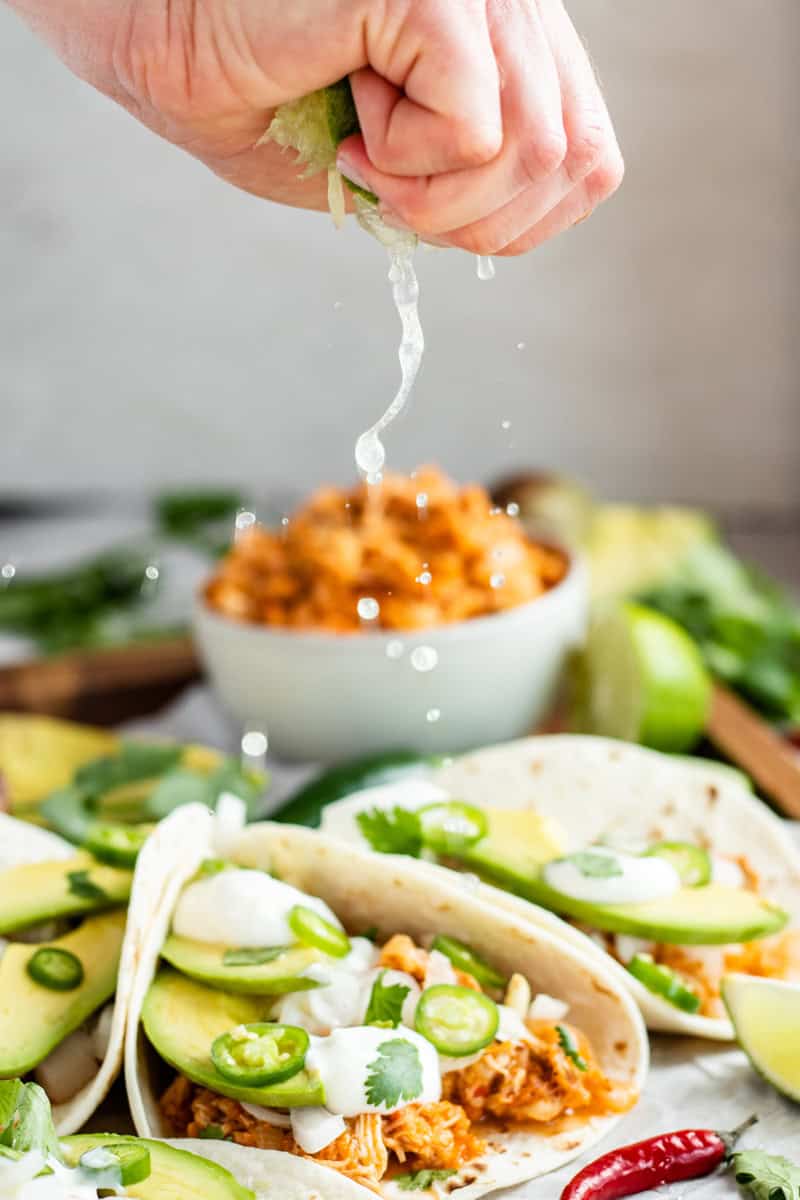 squeezing lime over chicken tinga in tortillas