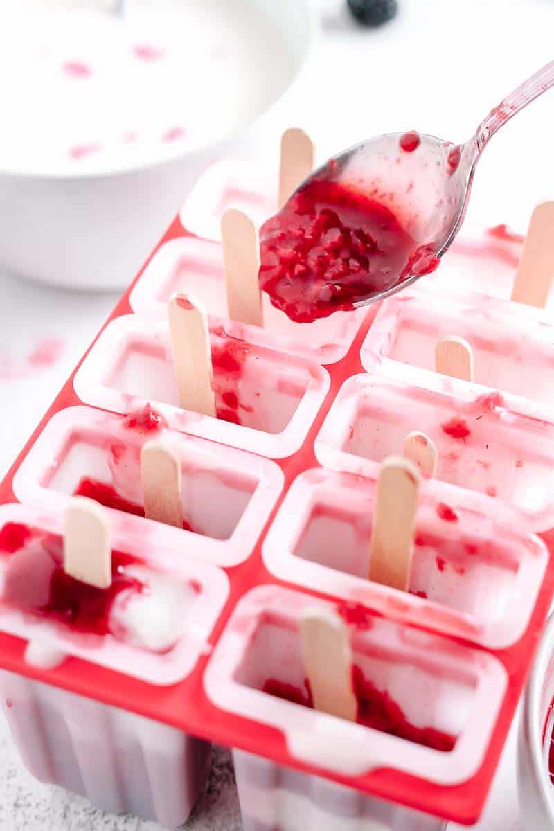 spooning mixed berry compote into popsicle molds